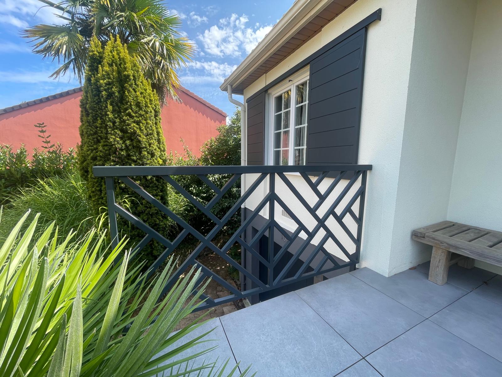 Terrasse avec balustrade métallique et arbres.