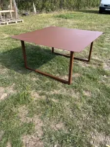 Table rouge en métal sur l'herbe.