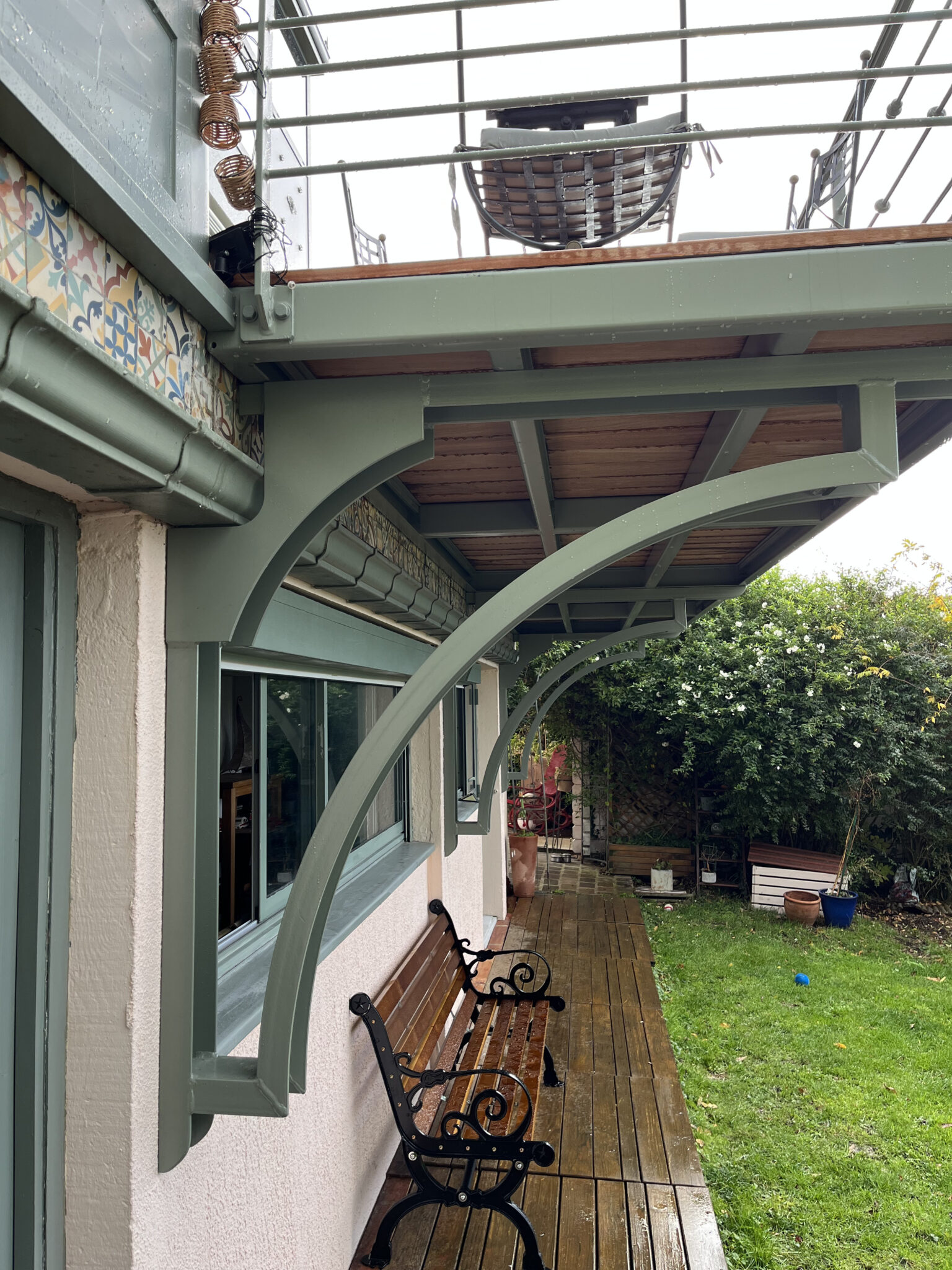 Terrasse avec bancs en bois et jardin verdoyant.
