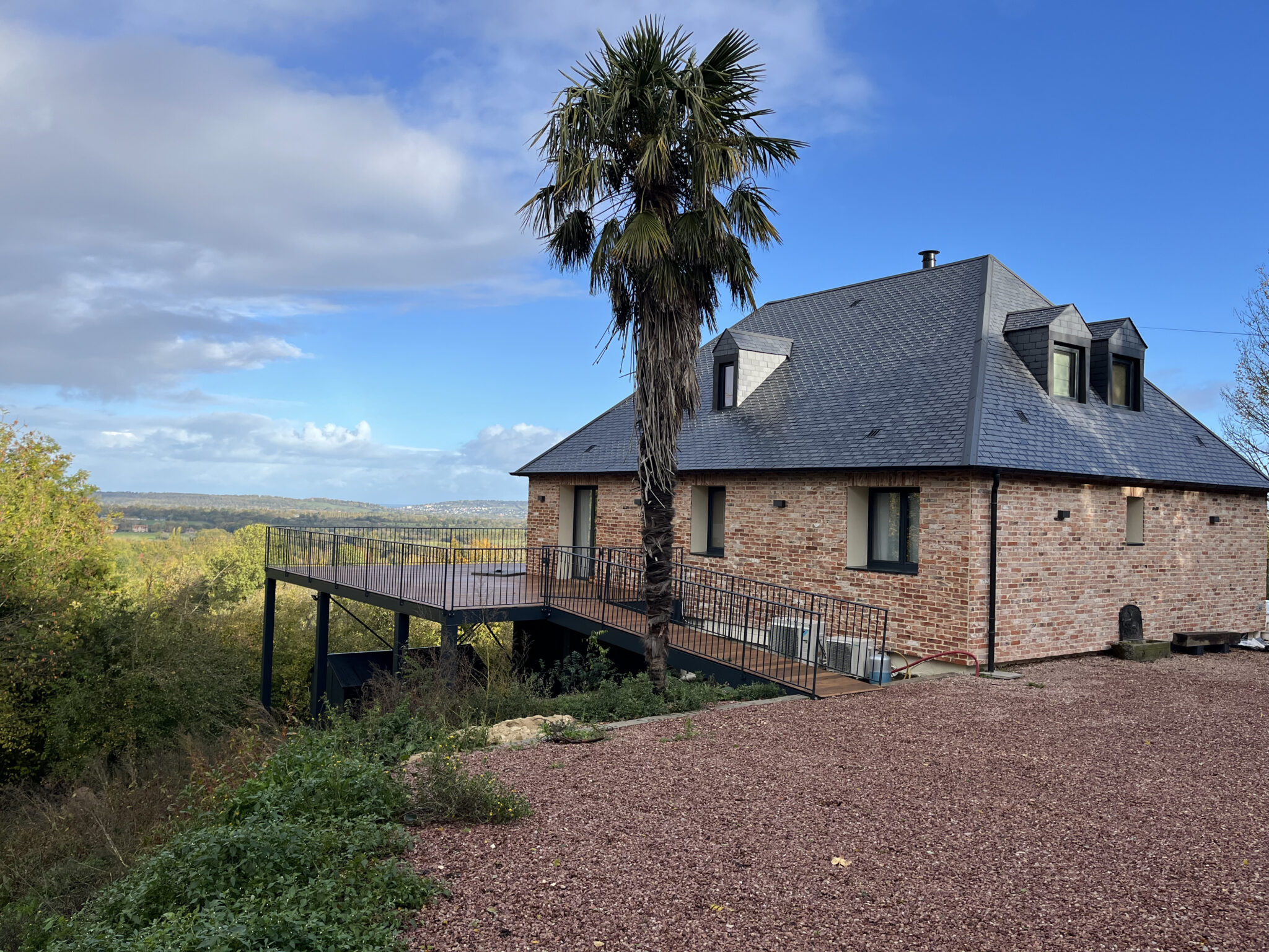 Maison en briques avec terrasse sur pilotis.