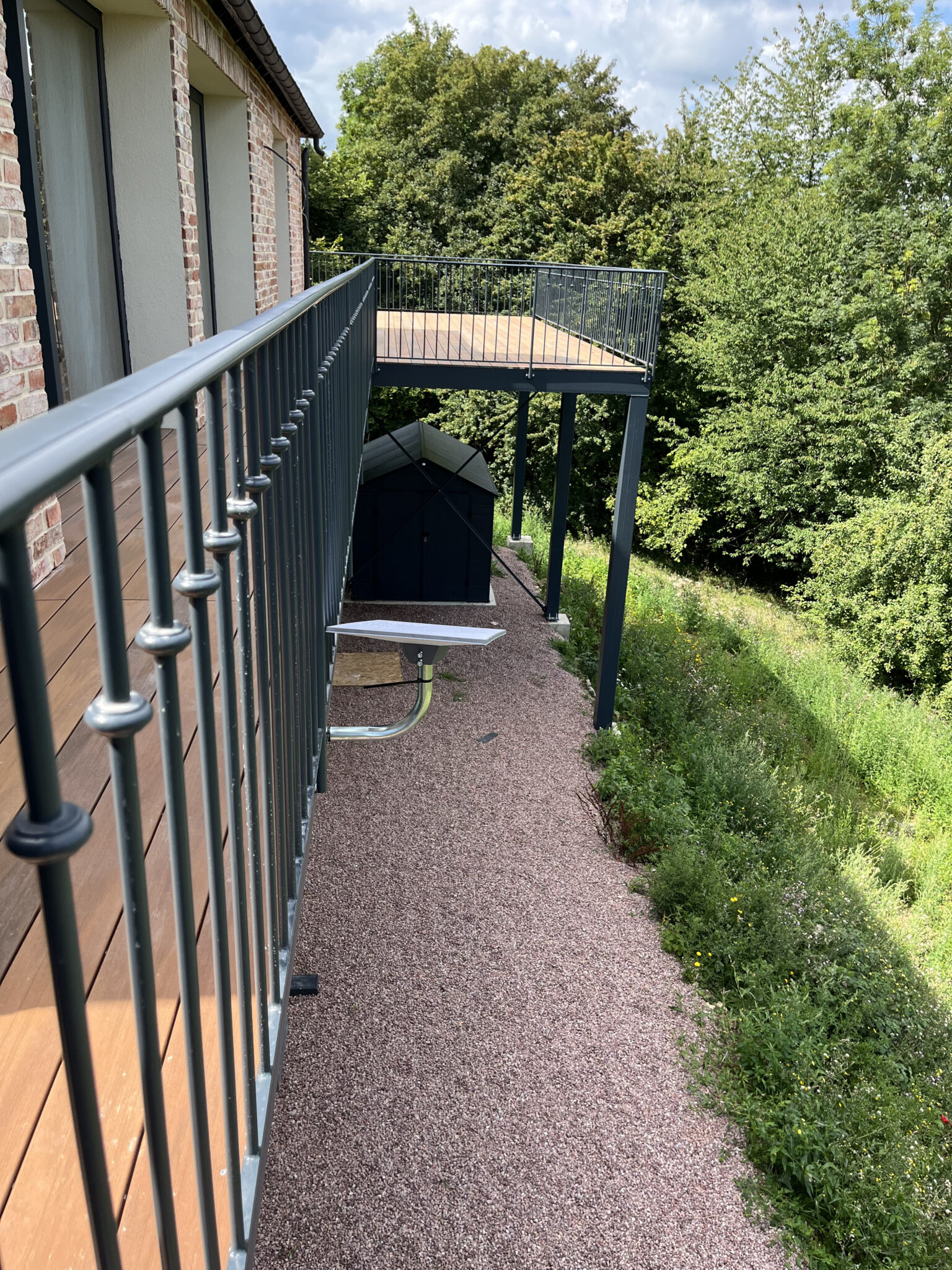 Terrasse en bois surplombant jardin verdoyant.