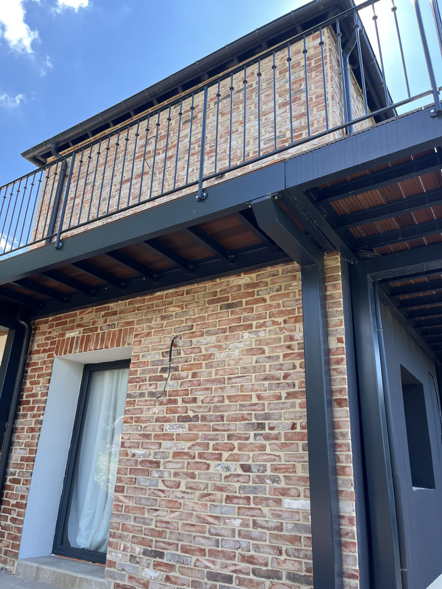 Façade en brique avec garde-corps métallique.